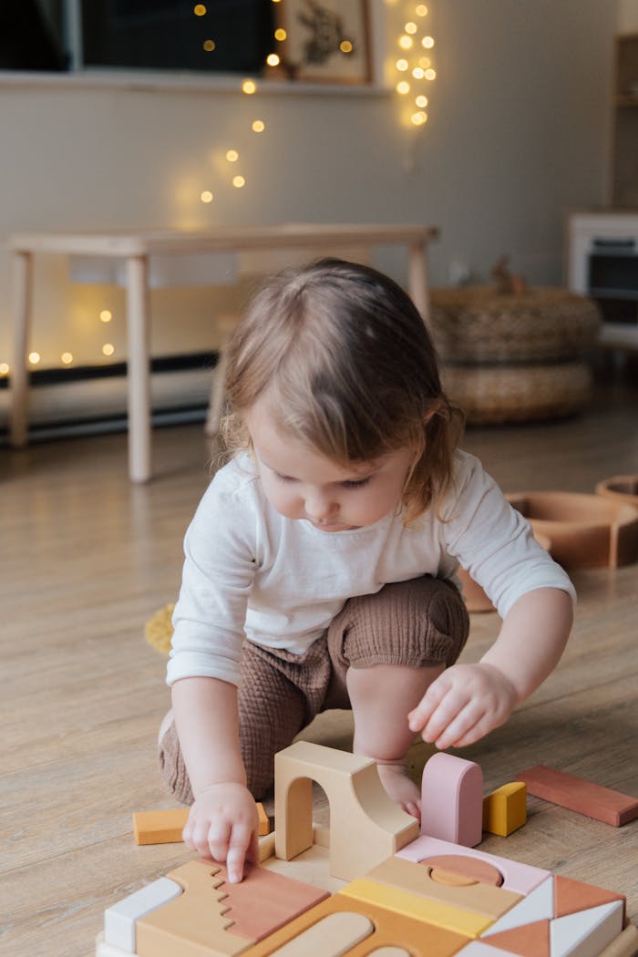 Adorable toddler immersed in play with wooden blocks, capturing a moment of childhood innocence indoors.
